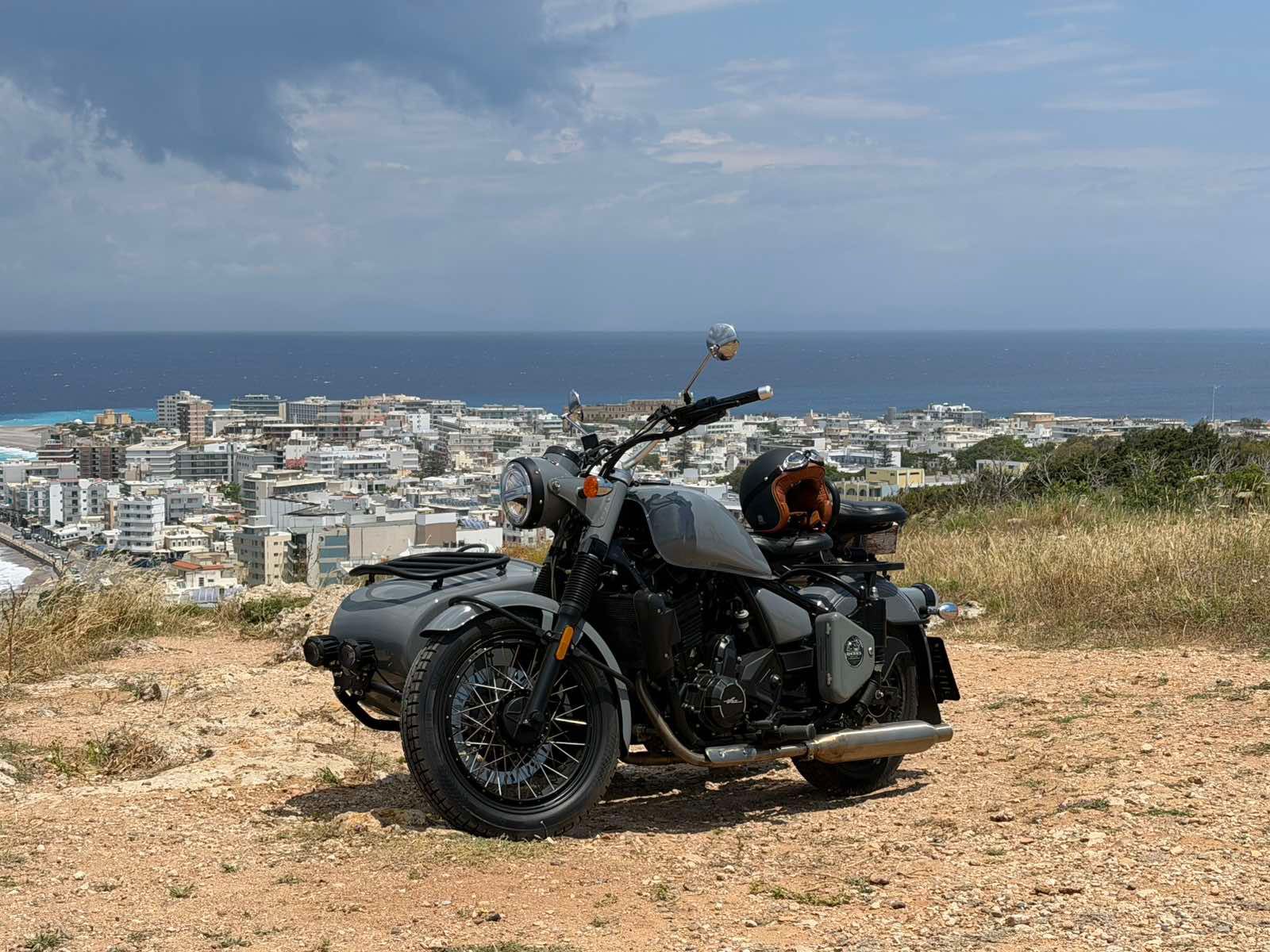 Vintage sidecar in front of a traditional Rhodes building with a Greek flag